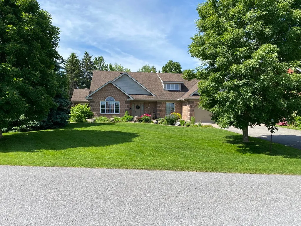 Brick home with a manicured front lawn and grounds